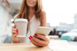 Woman drinking coffee and texting
